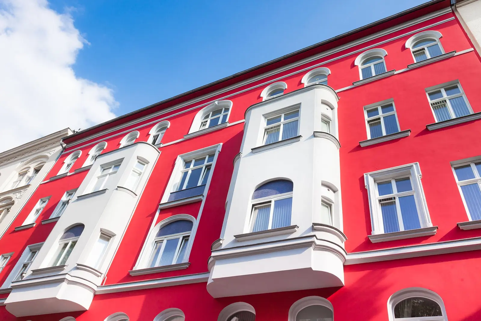 Rot gestrichene Altbaufassade mit weißen Fensterfaschen